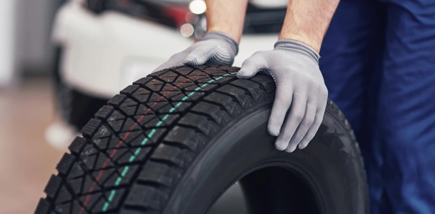 Trading Rubber closeup mechanic hands pushing black tire workshop